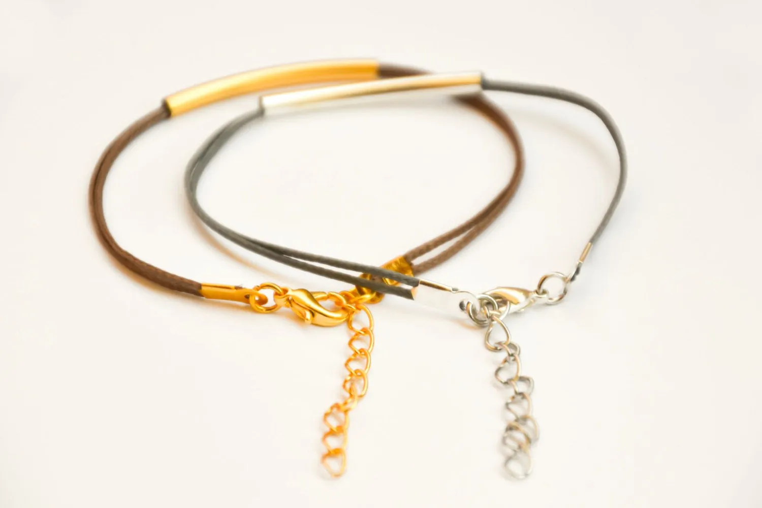 Silver and gold plated tube charms bracelets, gray and brown cords